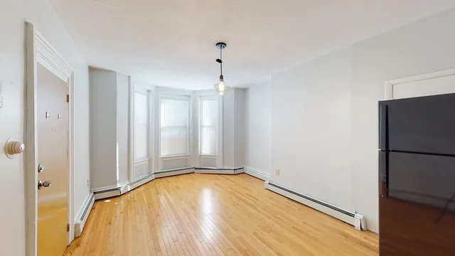 a view of empty room with wooden floor and window