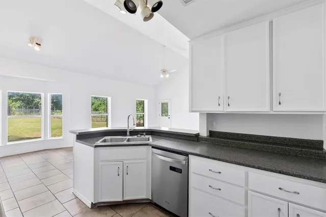 a kitchen with granite countertop white cabinets white appliances and a sink