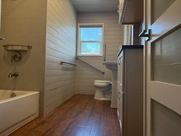an empty room with wooden floor fireplace and windows