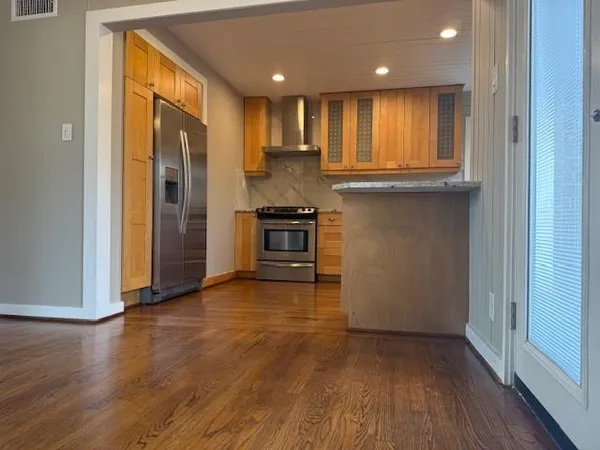 a view of kitchen with granite countertop stainless steel appliances counter space and wooden floor