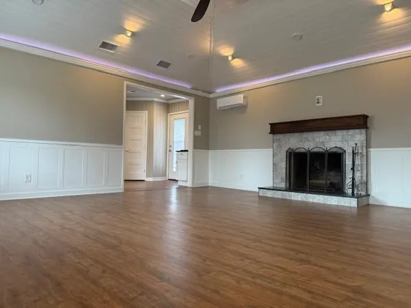 an empty room with wooden floor fireplace and windows