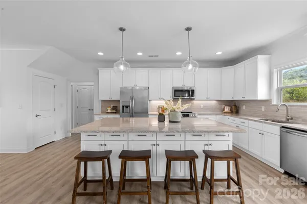 a kitchen with kitchen island granite countertop a dining table chairs and white cabinets