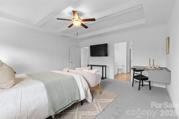 a bedroom with a bed a chandelier and a flat screen tv