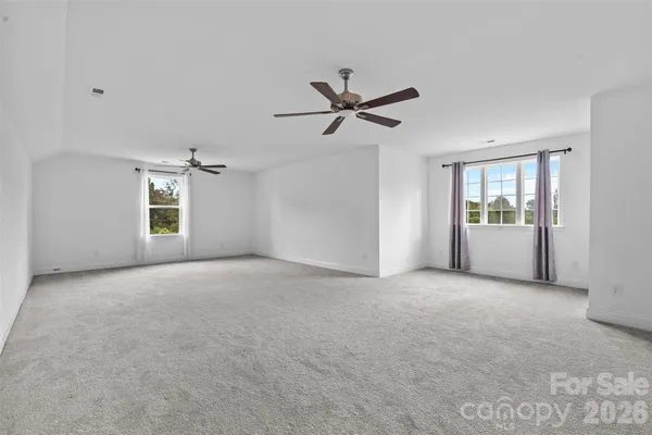 a view of a big room with windows and ceiling fan