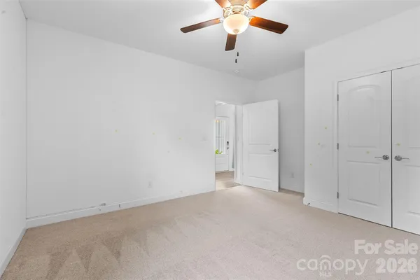 an empty room with a chandelier fan and windows