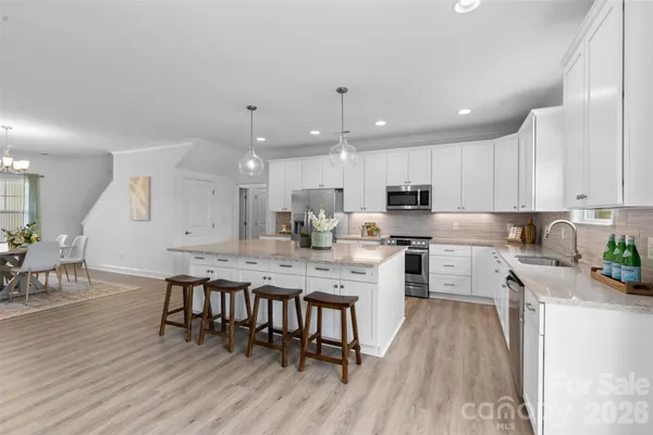 a kitchen with a dining table chairs wooden floor appliances and cabinets