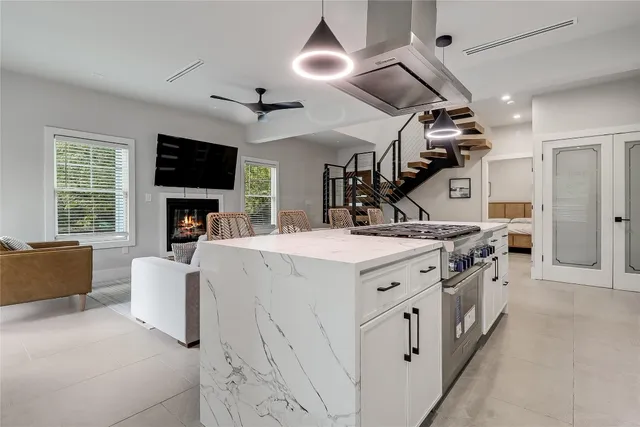 a large white kitchen with a stove and a large window