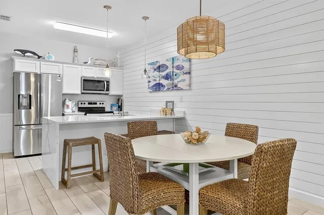 a kitchen with stainless steel appliances granite countertop a dining table chairs and a refrigerator