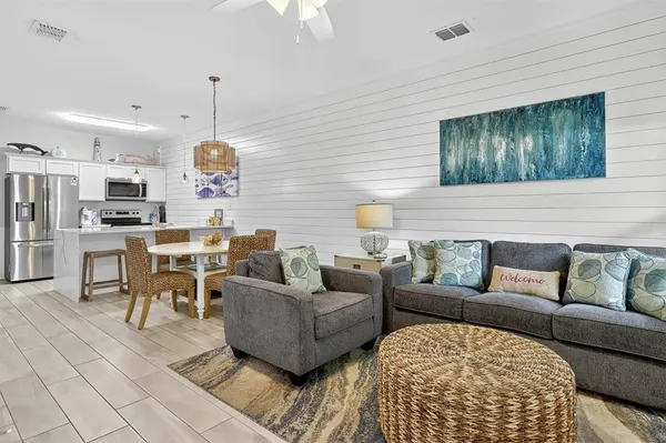 a living room with furniture kitchen view and a large window