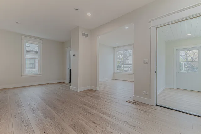 an empty room with wooden floor cabinet and windows