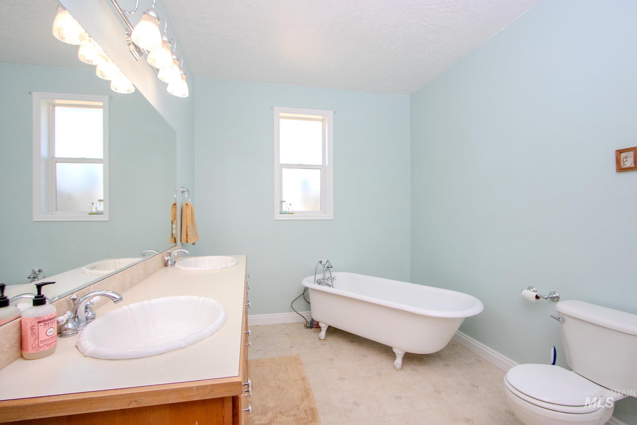 13569 Midway Road Nampa, ID 83651 - Photo 16 of 25 Full bathroom with a freestanding tub, double vanity, a textured ceiling, and tile patterned floors