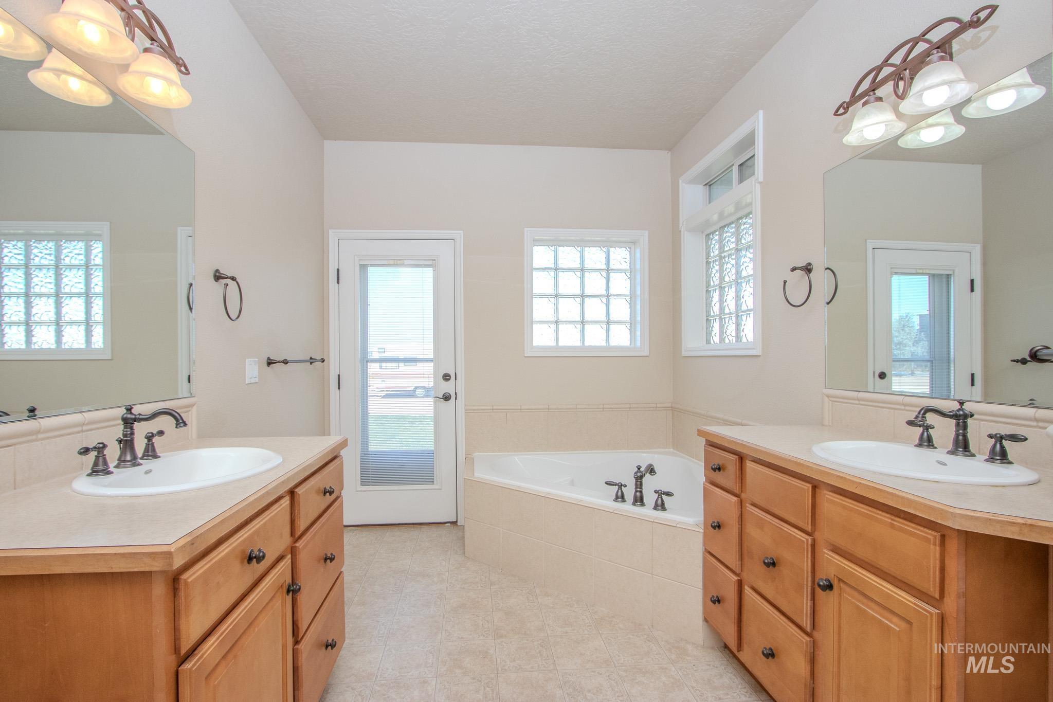 13569 Midway Road Nampa, ID 83651 - Photo 18 of 25 Full bath with two vanities, a chandelier, a garden tub, and a textured ceiling