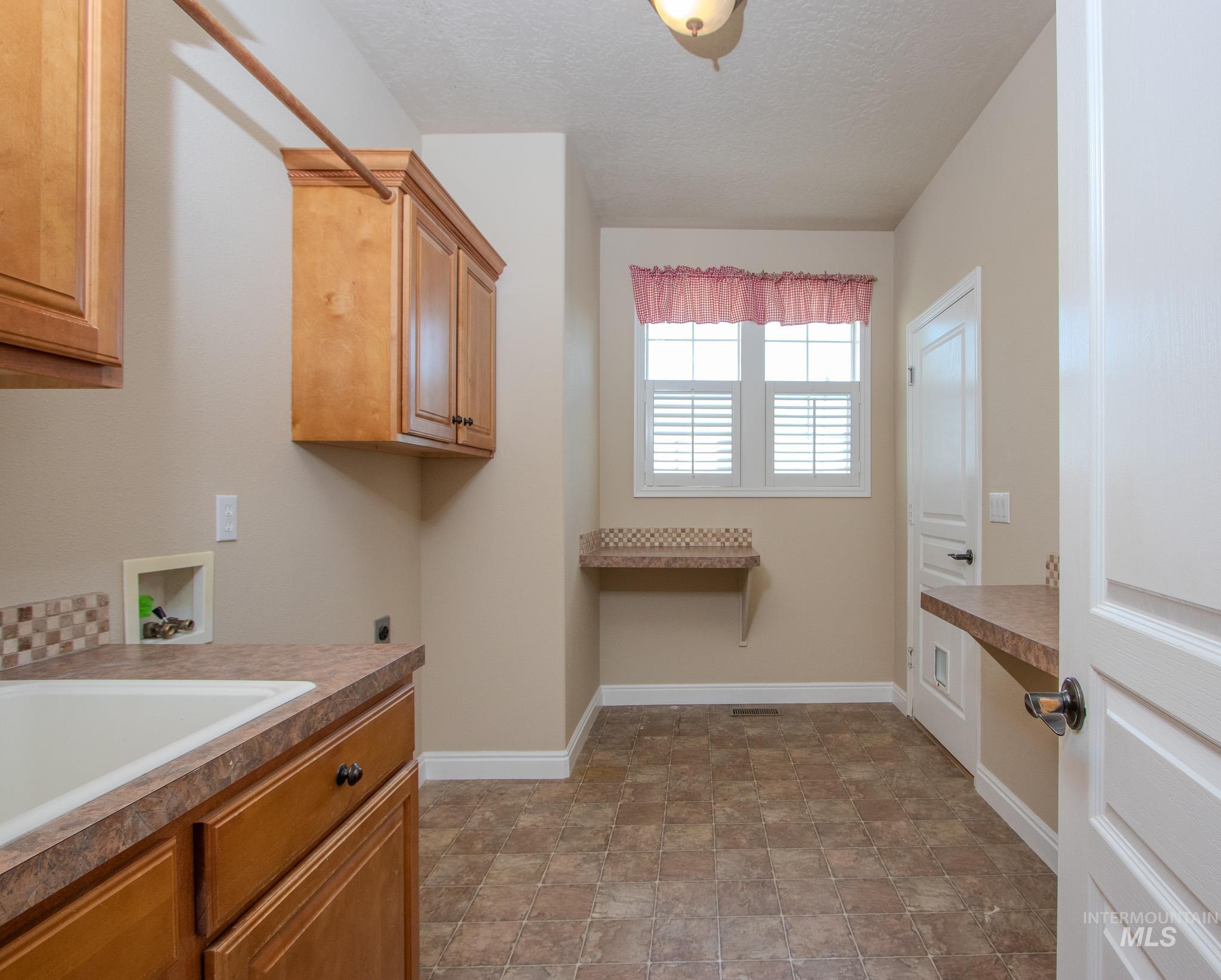 13569 Midway Road Nampa, ID 83651 - Photo 19 of 25 Laundry room featuring washer hookup, cabinet space, a textured ceiling, stone finish floors, and hookup for an electric dryer