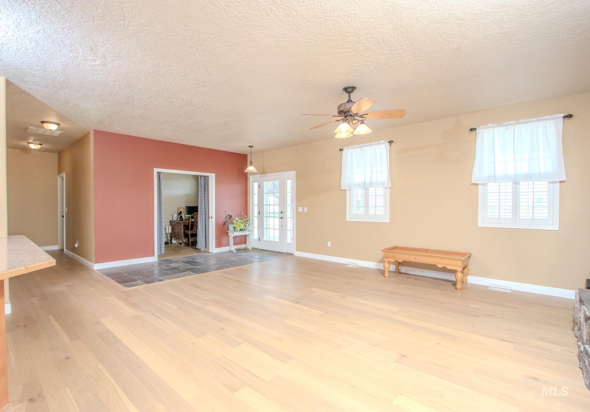 13569 Midway Road Nampa, ID 83651 - Photo 7 of 25 Unfurnished living room featuring a textured ceiling, light wood finished floors, and ceiling fan