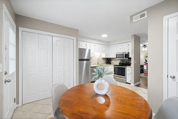a kitchen with stainless steel appliances a dining table chairs and refrigerator