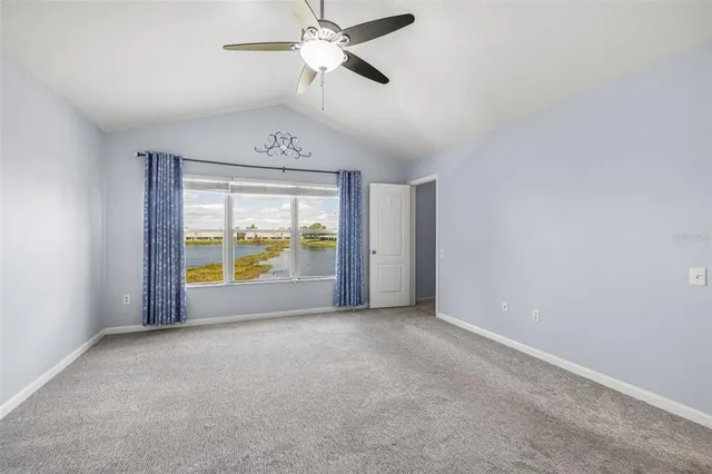 an empty room with a large window and a ceiling fan