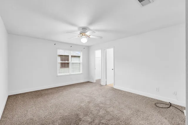 an empty room with windows and fan