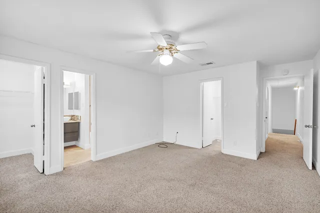a view of an empty room and chandelier fan