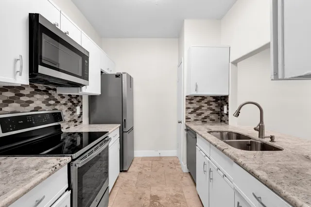a kitchen with stainless steel appliances granite countertop a sink stove and refrigerator