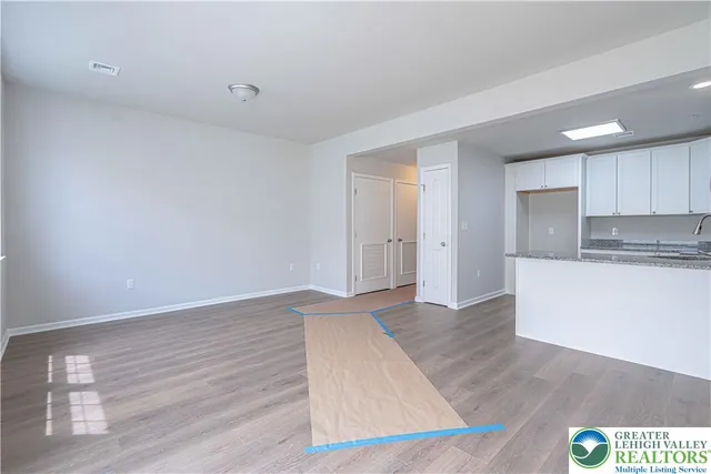 a view of an empty room with kitchen and a window