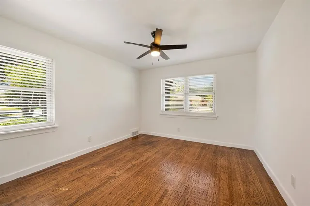 a view of empty room with wooden floor and fan