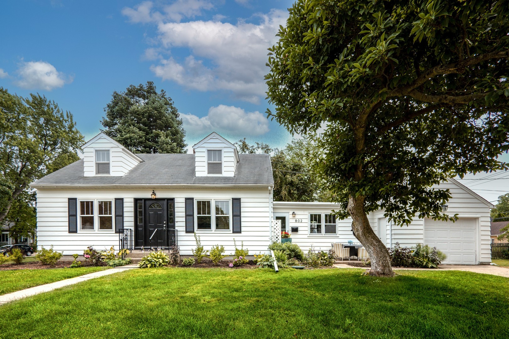a front view of a house with a yard and trees