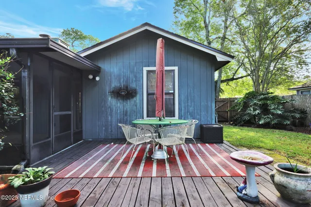 a view of a backyard with table and chairs potted plants and wooden fence