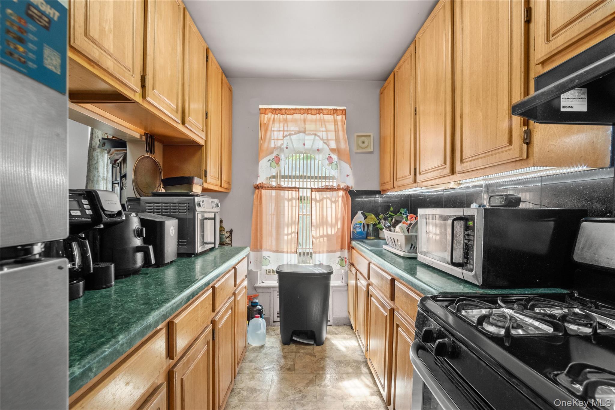 211 West 144th Street, Unit 2C Manhattan, NY 10030 - Photo 4 of 14 Kitchen featuring appliances with stainless steel finishes, tasteful backsplash, and under cabinet range hood