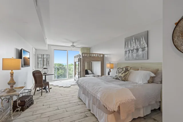 a bedroom with a bed a large window and wooden floor