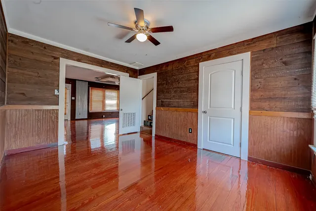 a view of empty room with wooden floor and fan