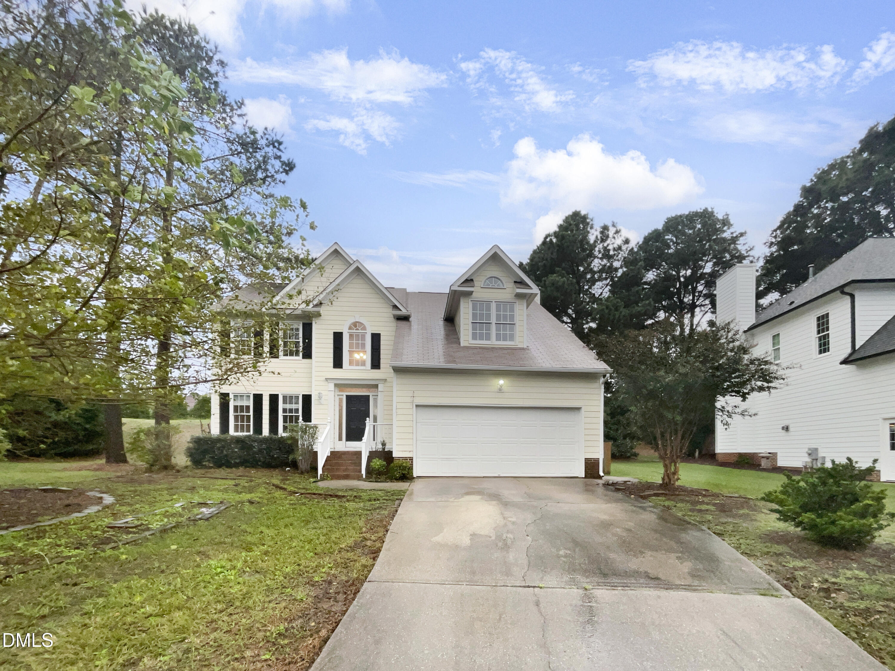 a view of a white house next to a yard with large trees