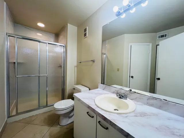 a bathroom with a granite countertop sink toilet and shower