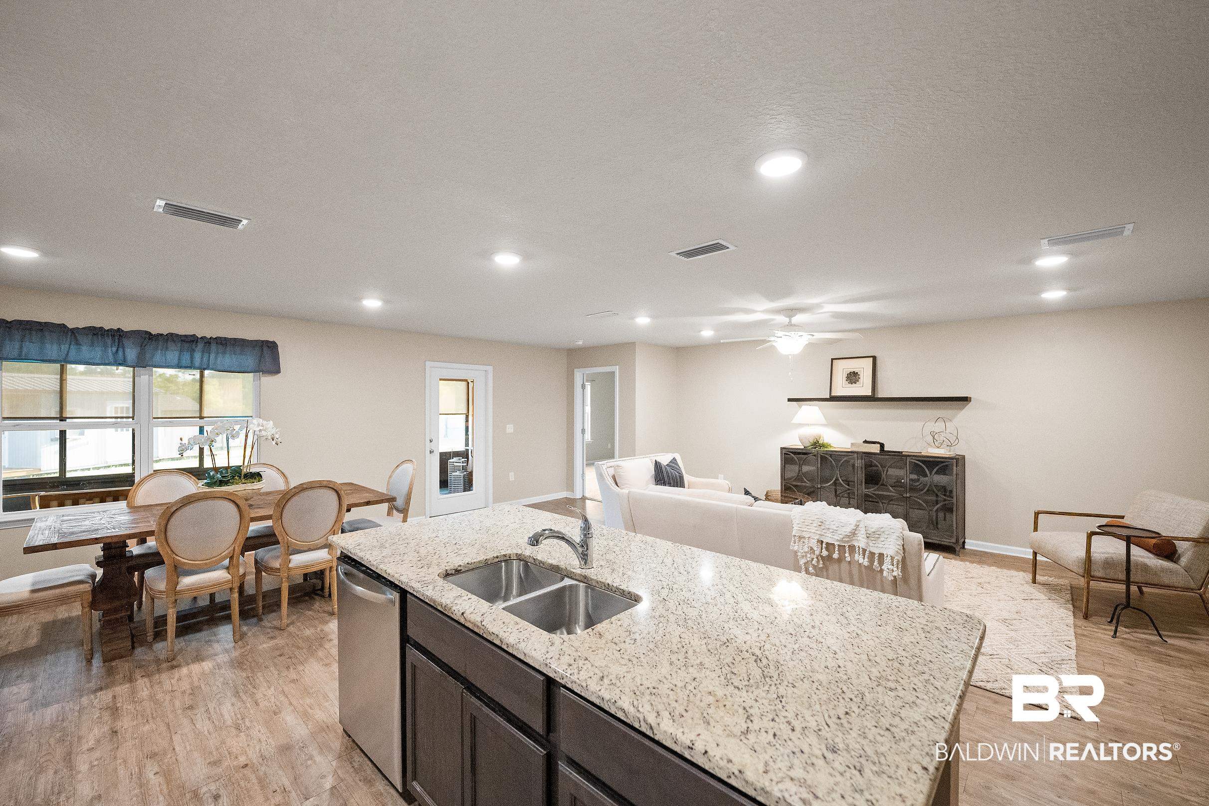 8294 Irwin Loop Daphne, AL 36526 - Photo 10 of 29 Open-concept living area featuring a kitchen island with dual basin sink, stainless steel dishwasher, and granite countertop