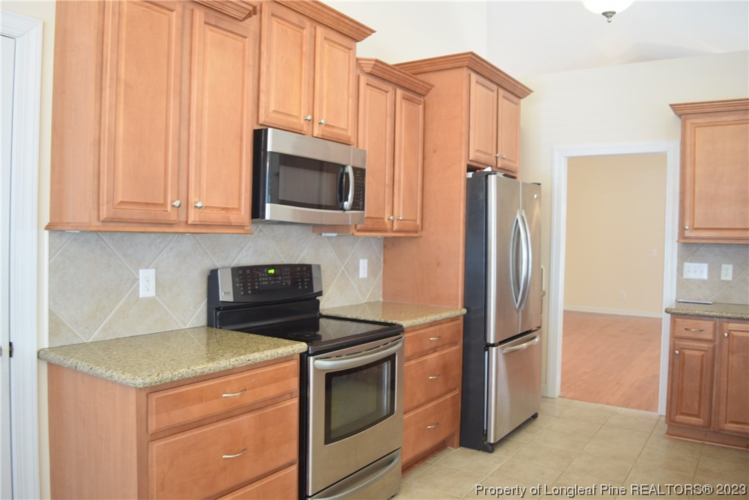 249 Rothbury Drive Whispering Pines, NC 28327 - Photo 8 of 26 a kitchen with stainless steel appliances granite countertop a refrigerator stove and microwave