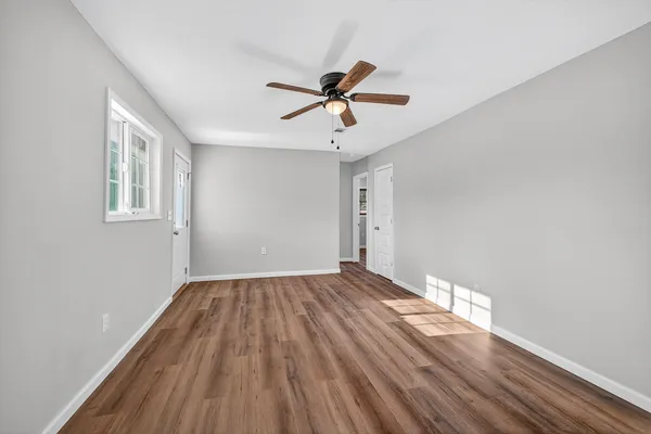 a view of empty room with wooden floor and fan