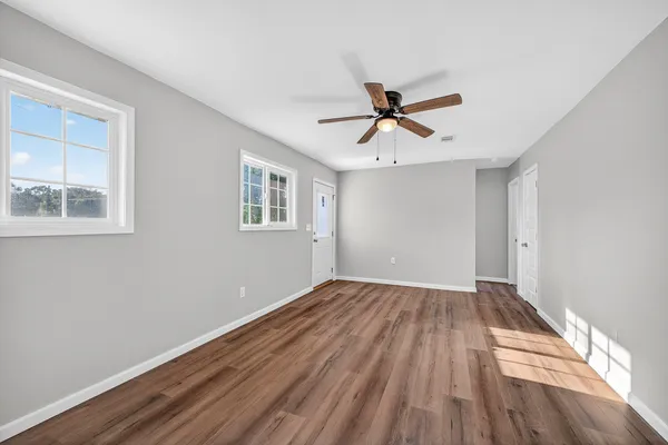 a view of empty room with wooden floor and fan