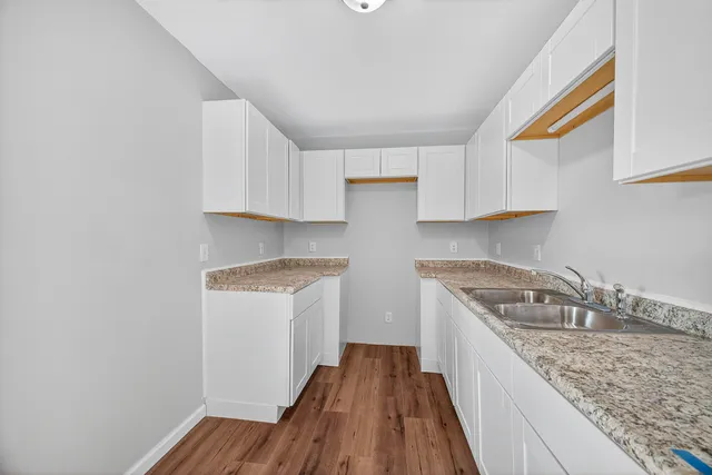 a kitchen with granite countertop a sink a stove and cabinets