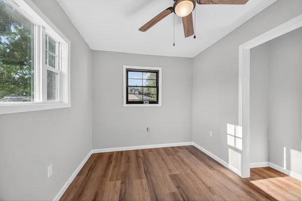 a view of empty room with wooden floor and fan