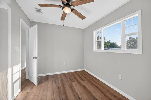 a view of an empty room with wooden floor and a window