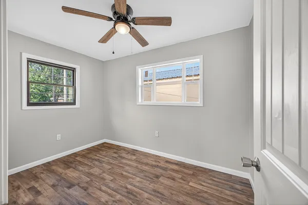 a view of empty room with wooden floor and fan