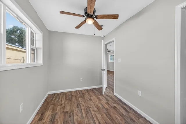 a view of empty room with wooden floor and fan