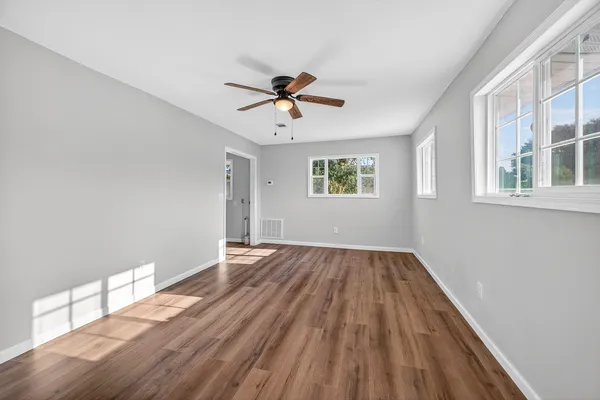 a view of empty room with wooden floor and fan