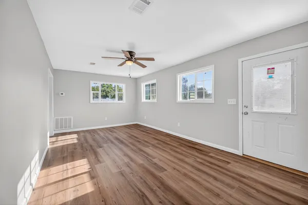 a view of empty room with wooden floor and fan