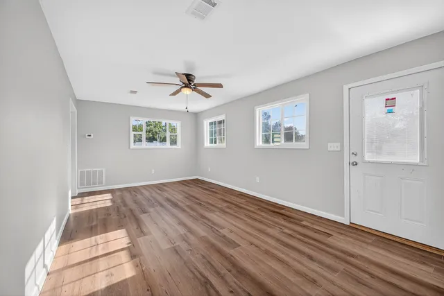 a view of empty room with wooden floor and fan