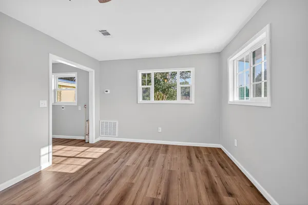 a view of empty room with wooden floor and fan