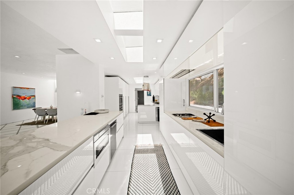 1046 North Hillcrest Road Beverly Hills, CA 90210 - Photo 21 of 74 a large white kitchen with stainless steel appliances granite countertop a lot of counter space and a sink