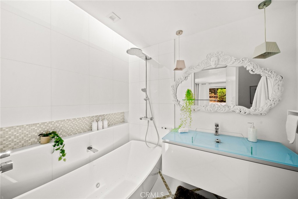 1046 North Hillcrest Road Beverly Hills, CA 90210 - Photo 61 of 74 a bathroom with a tub sink and mirror