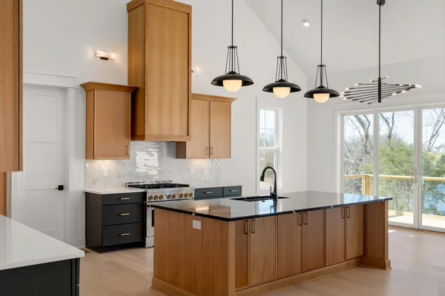 a kitchen with stainless steel appliances granite countertop a sink a stove and a wooden floor