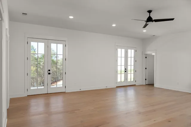 an empty room with wooden floor and ceiling fan