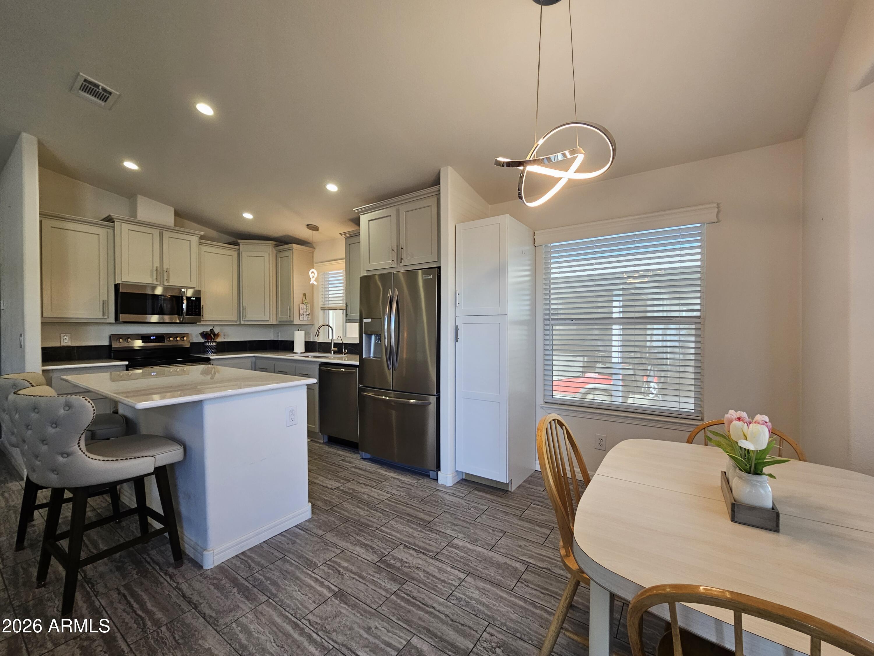 650 North Hawes Road, Unit 3223 Mesa, AZ 85207 - Photo 2 of 39 a kitchen with refrigerator a sink and chairs